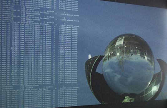 An image of an art projection with a glass ball and code on a wall